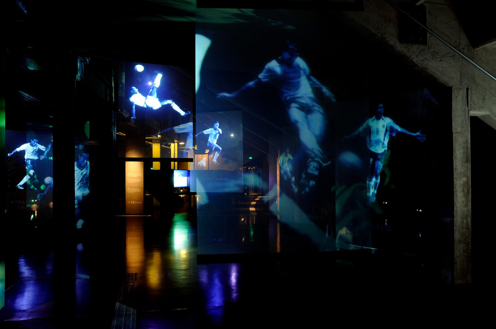 Sala escura com várias telas de jogadores ídolos do futebol brasileiro.