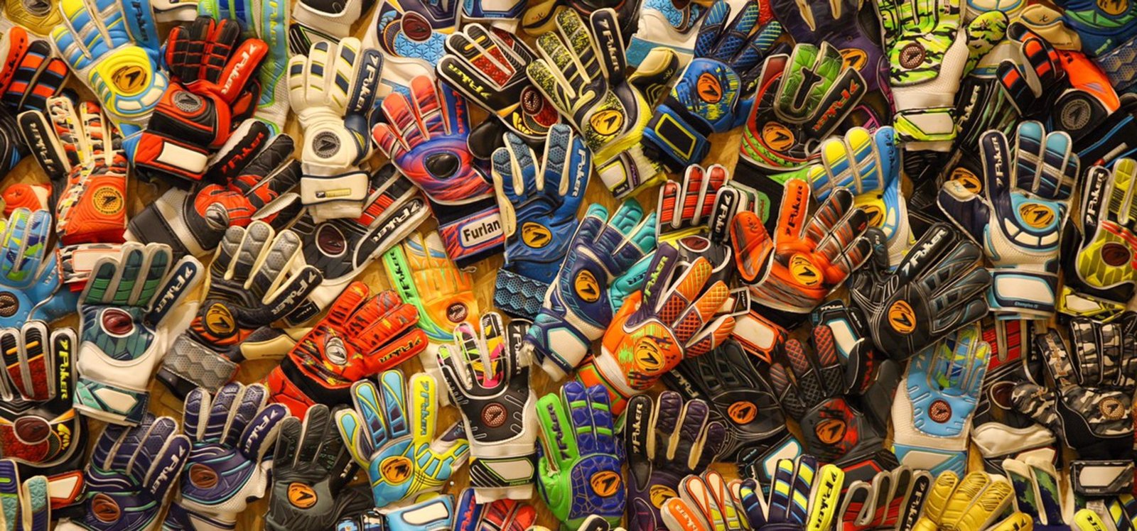 Parede forrada com várias luvas de goleiros, com efeito multicolorido.