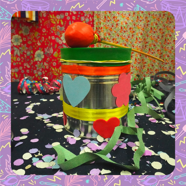 Fotografia de um tambor feito de lata e enfeitado com papel recortado em fortma de coração