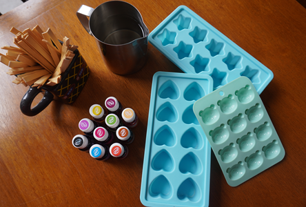 Foto mostrando três formas de gelo no formato de coração, gato e estrela, um vasilhame com água e tubinhos de tinta.