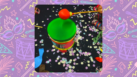 Imagem de um tampor de lata, com um tampo verde, e uma baqueta com a ponta vermelha