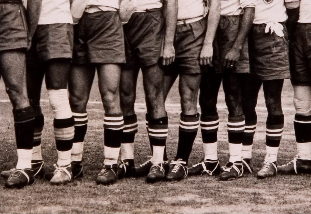 Imagem em preto e branco de pernas masculinas com chuteiras e meias