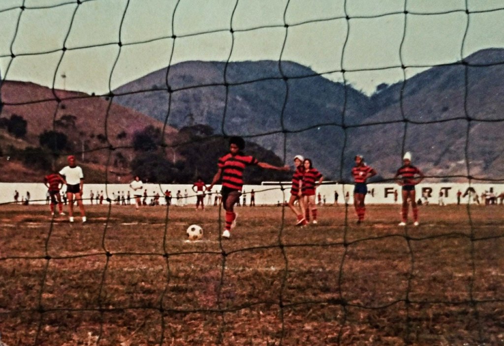Imagem de um campo de futebol e uma jogadora ao meio