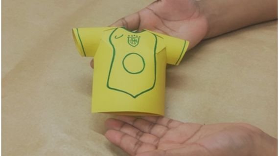 imagem com uma mão, ensinando fazer camisas de papel