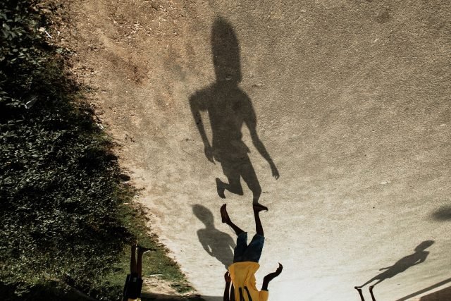 RuyRibeiroBarros Foto da sombra de uma criança jogando bola. A imagem está invertida; vemos a sobra de pé e a criança de cabeça para baixo, com a camisa amarela da Seleção Brasileira.