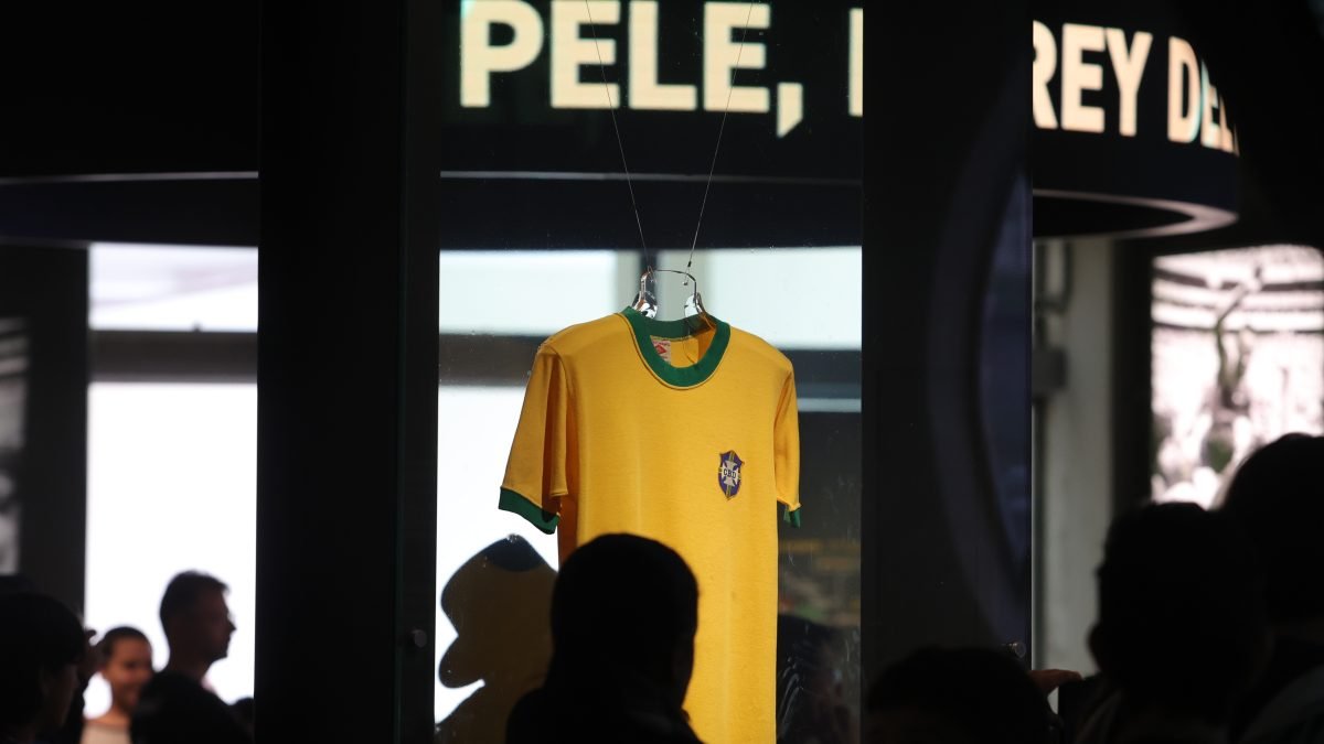 A camisa amarela de Pelé aparece ao fundo da imagem. Sobre ela, se lê um letreiro escrito "Pelé"