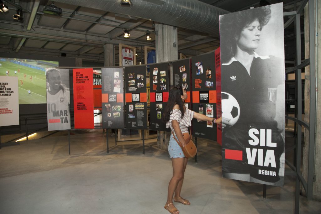 Uma mulher observa um painel com a foto da árbitra Silvia Regina na exposição Contra-Ataque: as mulheres do futebol