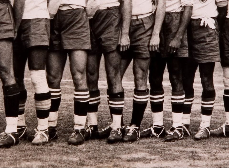 Imagem em preto e branco de pernas masculinas com chuteiras e meias