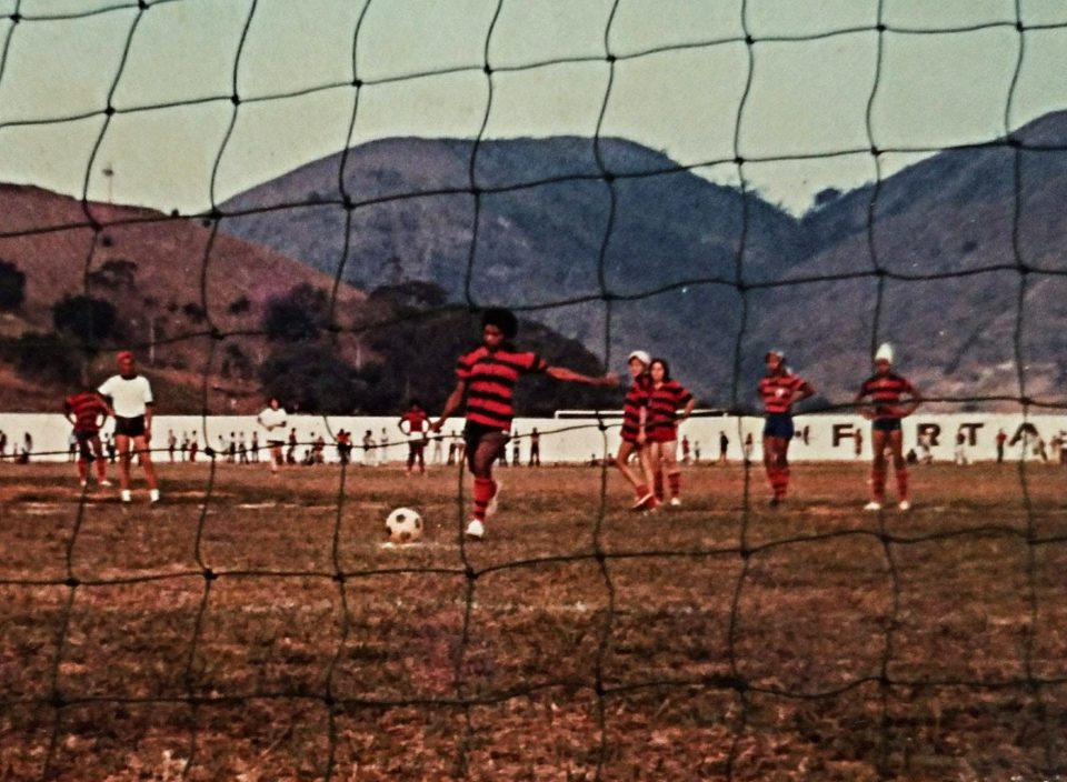 Imagem de um campo de futebol e uma jogadora ao meio