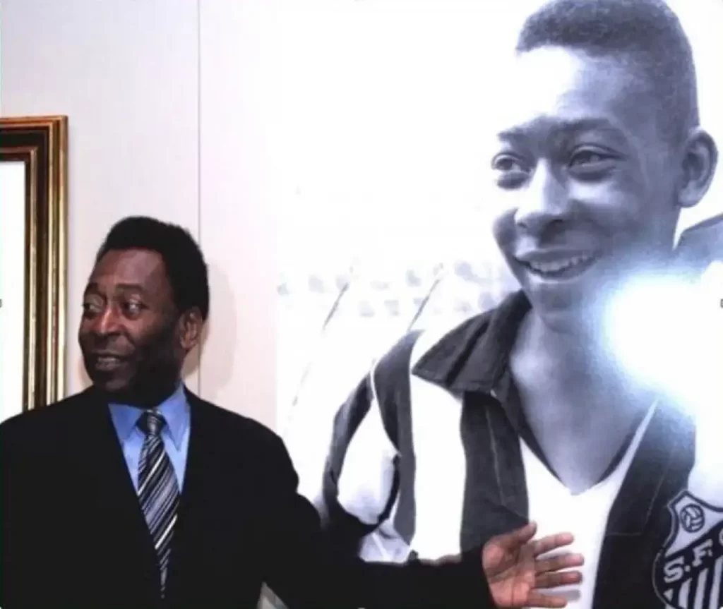 Foto de Pelé vestido de terno escuro ao lado de uma grande foto dele mais jovem, em preto e branco, usando a camisa do Santos.