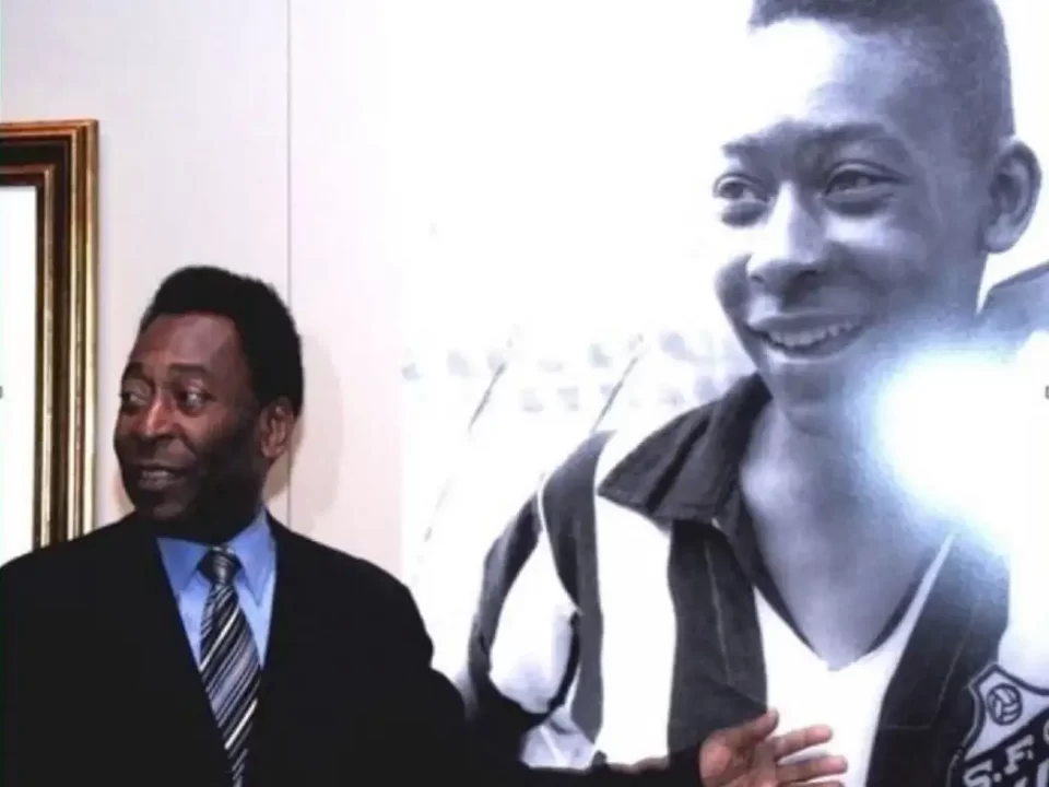 Foto de Pelé vestido de terno escuro ao lado de uma grande foto dele mais jovem, em preto e branco, usando a camisa do Santos.