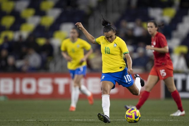 Marta com a camisa da Seleção em uma partida, preparando-se para chutar a bola.