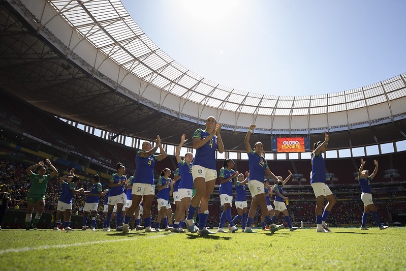 Seleção Brasileira feminina entrando no gramado de um estádio de futebol, com os uniformes azuis.