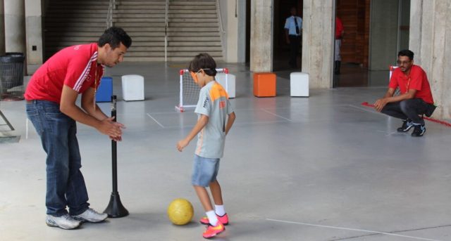 Imagem de uma criança e um adulto realizando a atividade Artilheiro Adaptado.