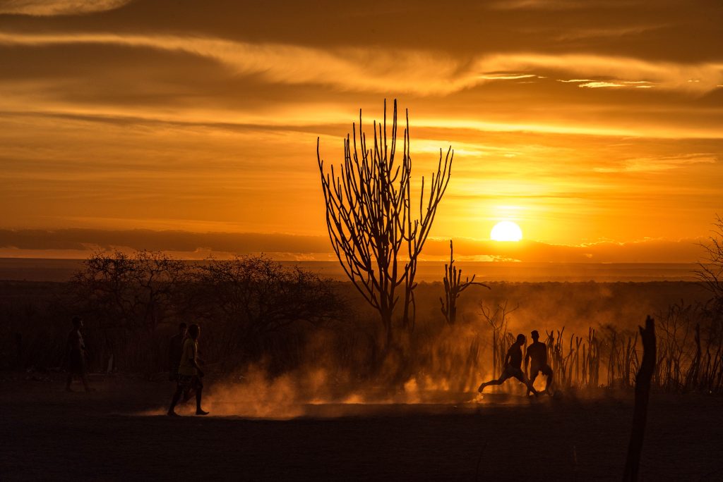 Ao pôr-do-sol do sertão duas crianças disputam a bola.