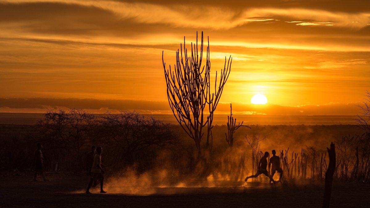 Ao pôr-do-sol do sertão duas crianças disputam a bola.