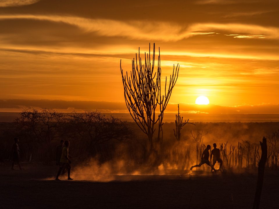 Ao pôr-do-sol do sertão duas crianças disputam a bola.