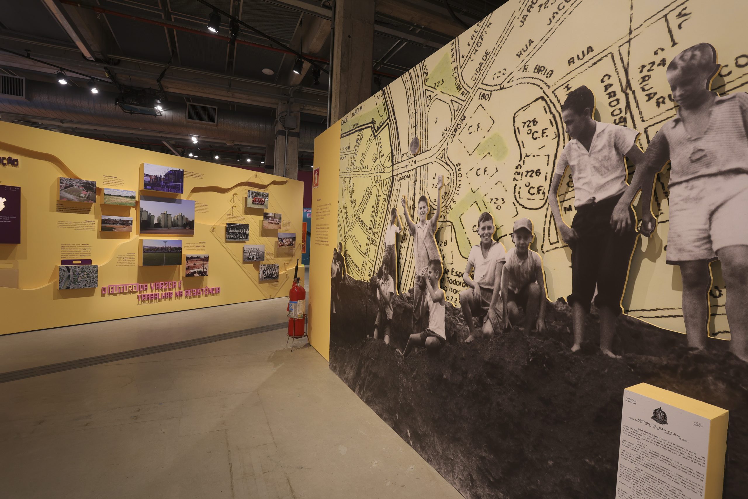 Painel composto por um fundo de mapa antigo da cidade e na frente fotos em preto e branco de pessoas.