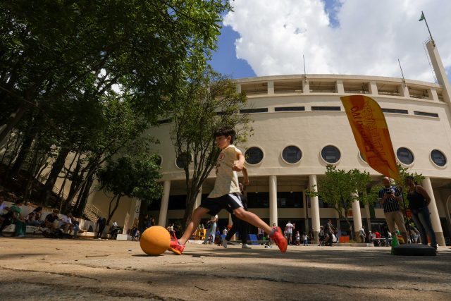 Imagem de uma criança chutando uma bola na área externa do Museu do Futebol