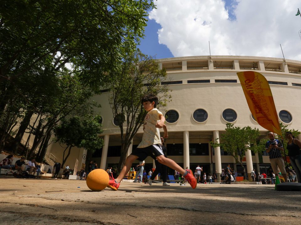 Imagem de uma criança chutando uma bola na área externa do Museu do Futebol