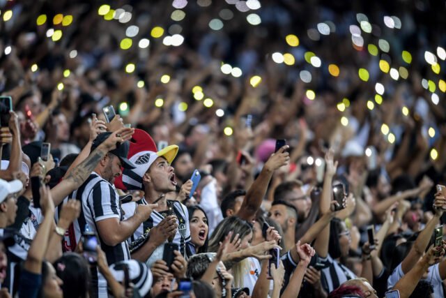 118_MuseudoFutebol-FredMagno Em um estádio lotado, torcedores levantam seus celulares com as lanternas ligadas. Por toda a imagem, se vê os pontos de luz.