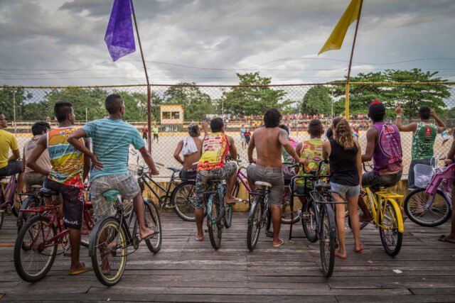 158_FOTO_AndersonCoelho Torcedores assistem a uma partida de futebol de várzea. O detalhe interessante é que todos eles estão montados em bicicletas. Eles estão de costas para o fotógrafo.