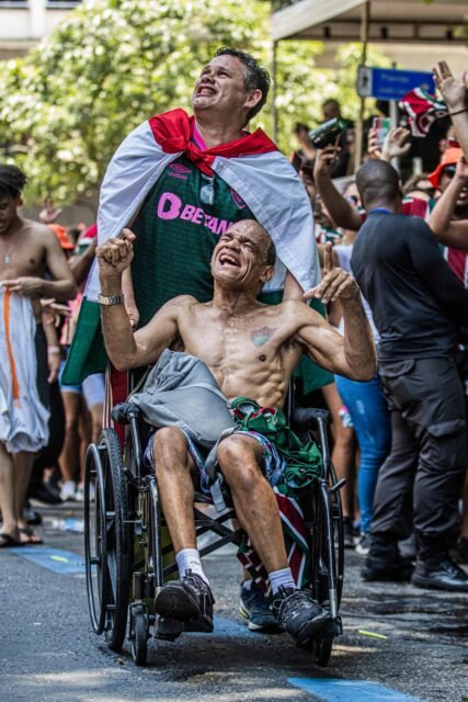 196_FOTO_MarinaGarcia Dois torcedores do fluminense muito emocionados. Um deles está de pé e enrolado em uma bandeira. O outro é cadeirante, está sem camisa e tem uma tatuagem com o símbolo do clube no peito.