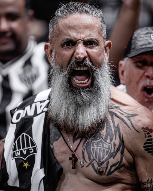 73_CRIS MATTOS-7781-3-cristianemattos Um torcedor do Atlético Mineiro em close, grita. Ele tem a camisa pendurada no ombro, tem o símbolo do clube tatuado no peito e uma longa barba branca.