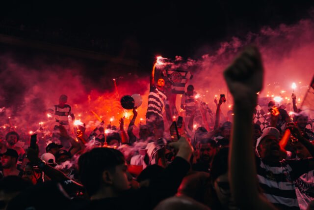 80_FOTO_EvanderPortilho-EvanderPortilho Uma torcida solta sinalizadores à noite e fica iluminada por uma bruma vermelha