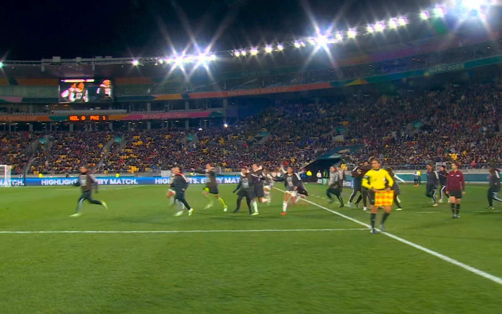 imagem aberta de um campo de futebol. pessoas correm nele coemmorando algo