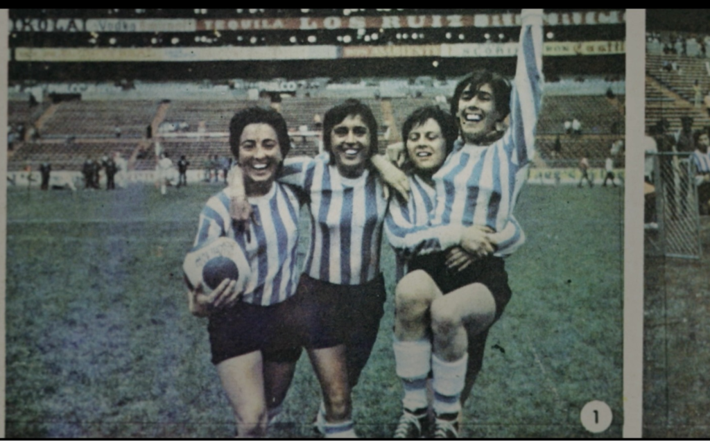 foto de quatro jogadoras vestindo a camisa da argentina em um campo de futebol