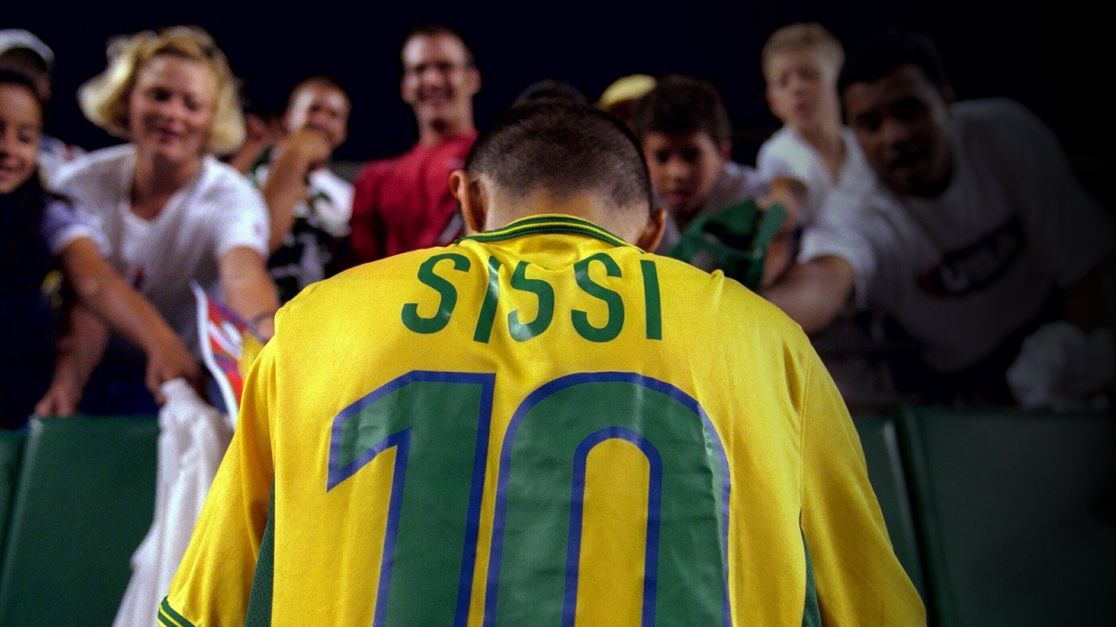 Imagem da jogadora Sissi, vestindoa camisa da seleção e de costas, autografando