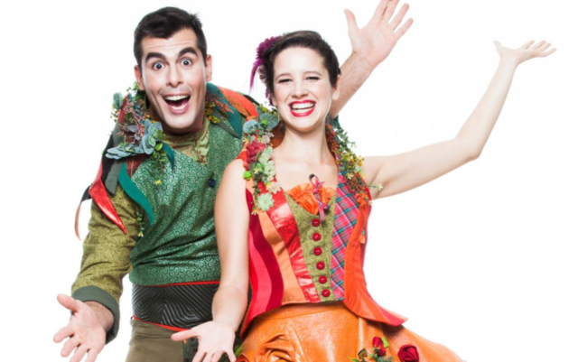 foto dois dos integrantes do Bailinho da Trupe. Um homem que veste uma fantasia verde e uma mulher, que veste fantasia laranja.