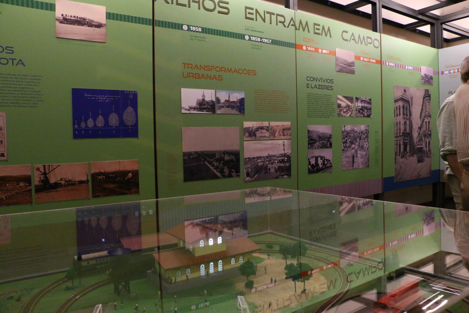 Imagem da Exposiçãp rtilhos da Bola. No centro da foto há uma mesa, com u ma maquete do Museu e ao fundo, painel com um dos eixos da exposição.