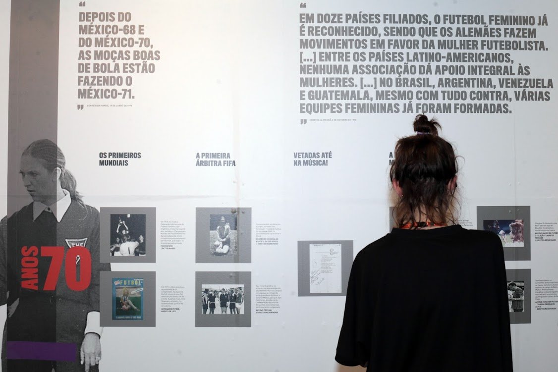 santos Mulher de costas, observa um dos painés da exposição.